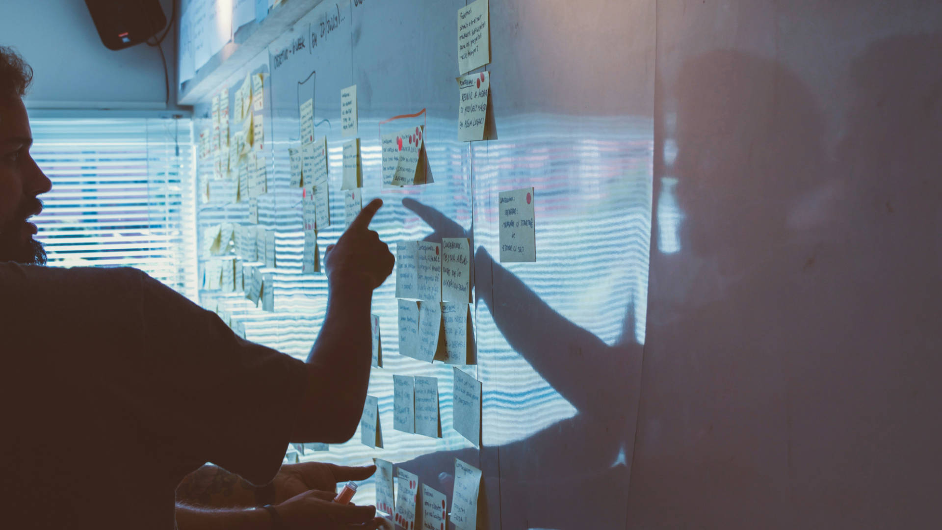 Someone pointing at a whiteboard covered with post it notes